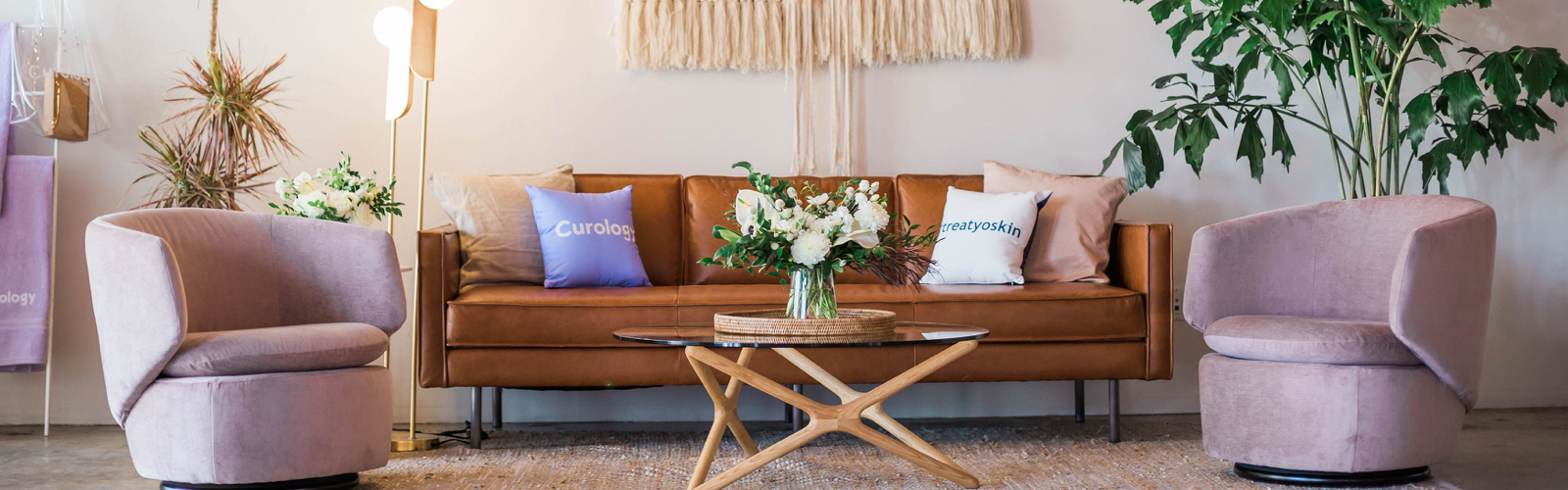 A living room with a brown leather couch in the center and two lavendar arm chairs on either side.